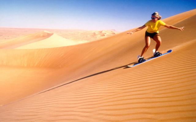 A woman desert sandboarding in Dubai